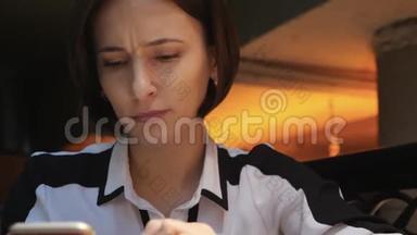 年轻迷人的女人在一家舒适的咖啡馆里使用她的手机。 她既惊讶又愤怒